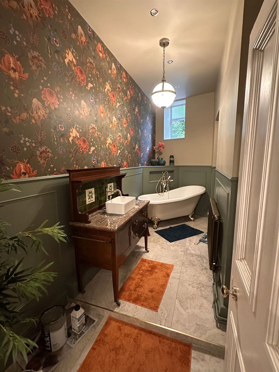 Elegant bathroom with floral wallpaper and freestanding bath